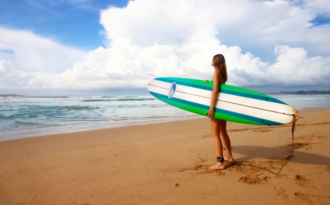 サーフボードを砂浜で持つ女性